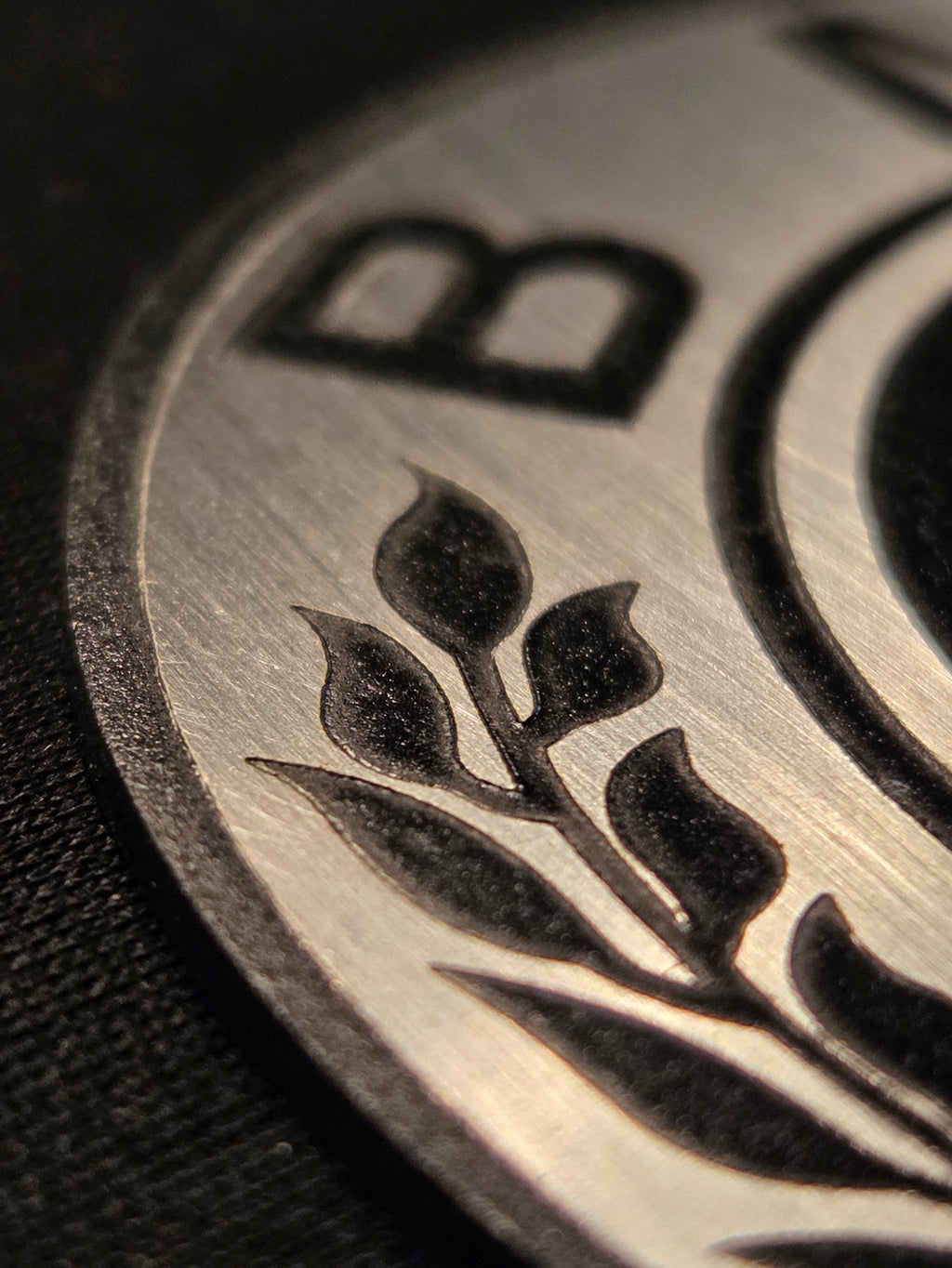 Close-up of a metallic object with engraved design on a black background