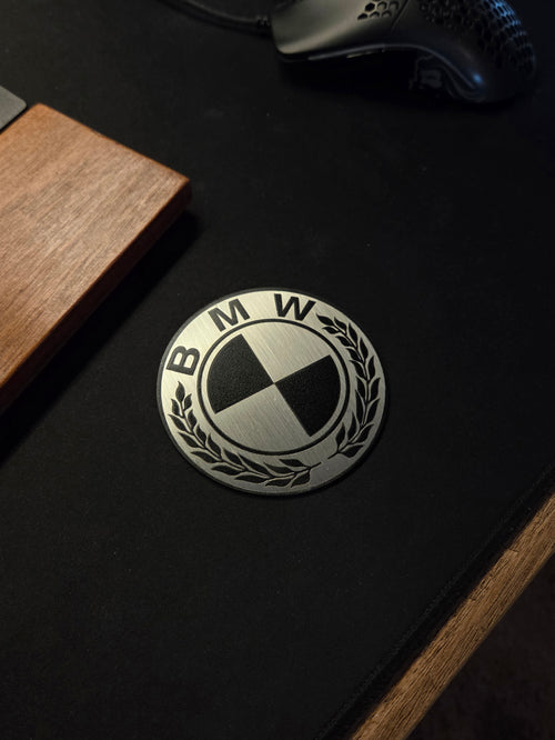 BMW logo on a black surface with wooden and metallic objects around